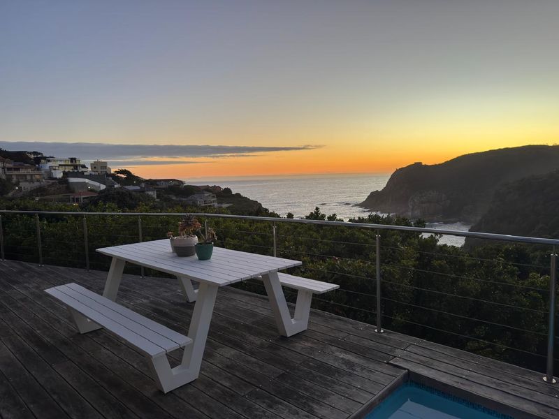 Elevated timber deck featuring a swimming pool and stainless steel railing, offering expansive coastal and sunset views.
