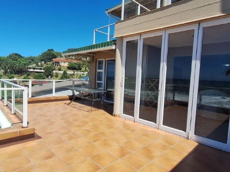 Spacious outdoor balcony featuring tiled flooring, a modern glass balustrade, and large folding glass doors providing seamless access to the interior.