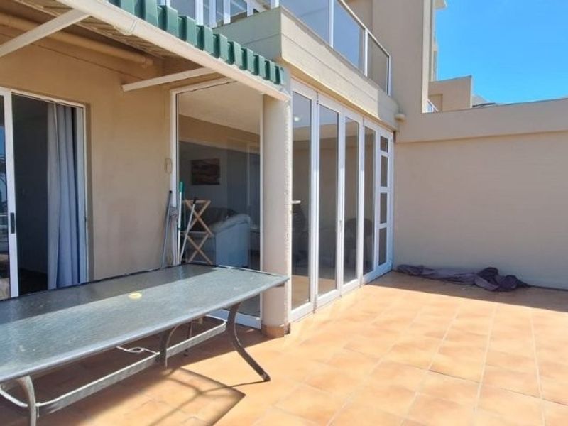 Spacious outdoor balcony featuring tiled flooring, glass balustrades, and large sliding glass doors providing seamless access to the interior living space.