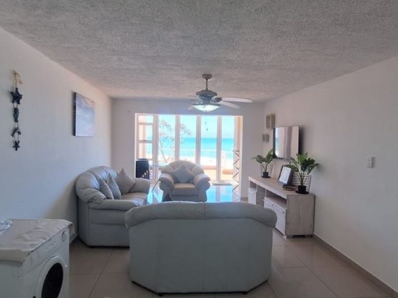 Spacious living area featuring tiled floors, a ceiling fan, and large sliding glass doors that provide natural light and access to the balcony.