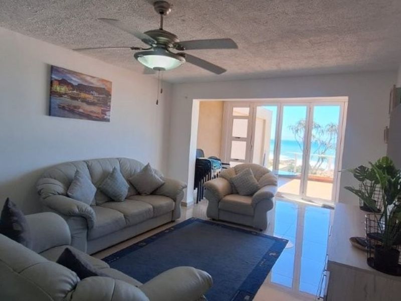 A comfortable living room featuring tiled flooring, a ceiling fan, and large sliding glass doors that provide natural light and access to the balcony.