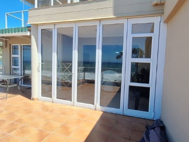 A spacious tiled balcony featuring large folding glass doors that provide seamless access to the interior and offer expansive outdoor views.
