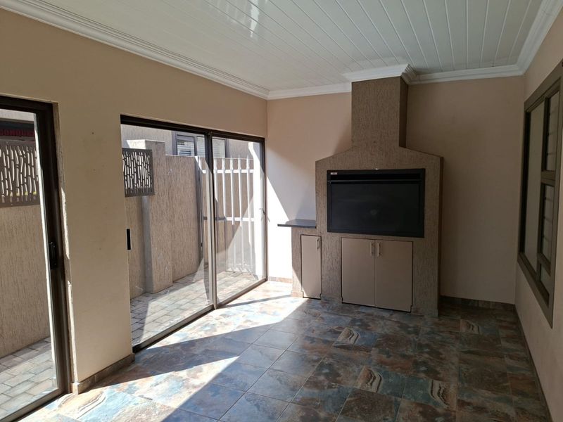 A covered patio area featuring a built-in braai, tiled flooring, and sliding glass doors leading to an outdoor space.