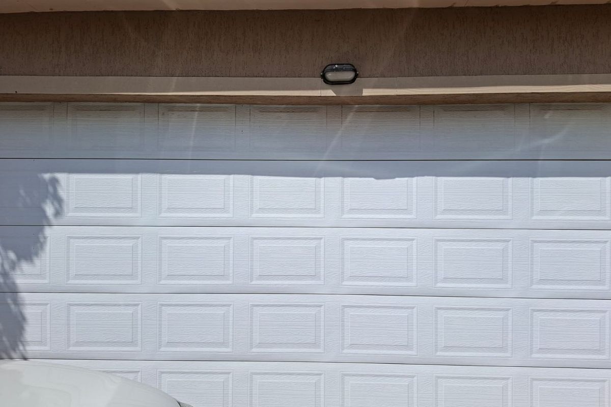 A close-up view of a white sectional garage door with a mounted exterior light fixture above.