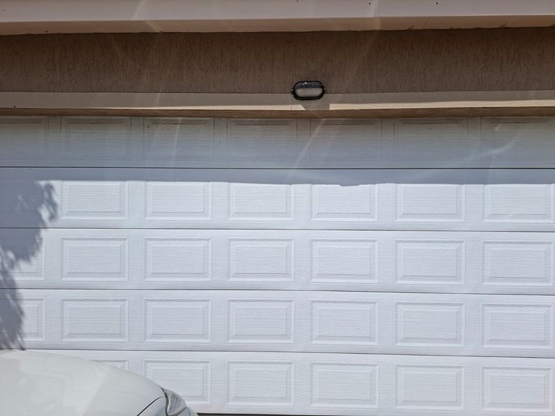 A close-up view of a white sectional garage door with a mounted exterior light fixture above.