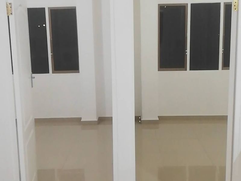 A bright, empty hallway featuring neutral tiled flooring and two doorways leading into adjacent rooms with windows.