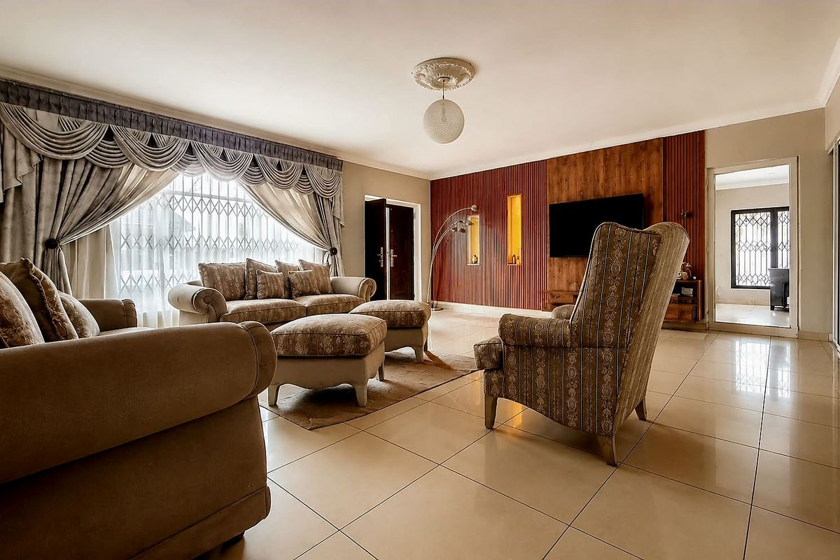 Spacious living room featuring polished tile flooring, decorative ceiling detailing, and a feature timber-paneled wall with integrated display niches.