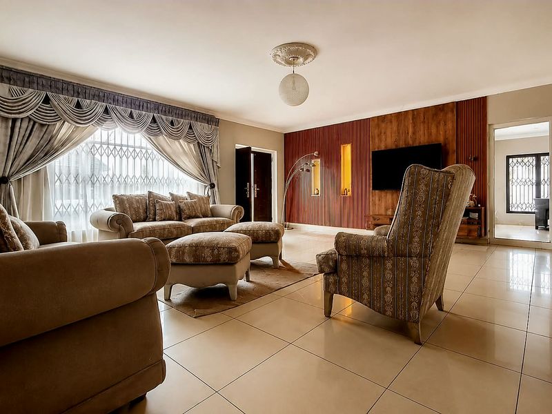 Spacious living room featuring polished tile flooring, decorative ceiling detailing, and a feature timber-paneled wall with integrated display niches.