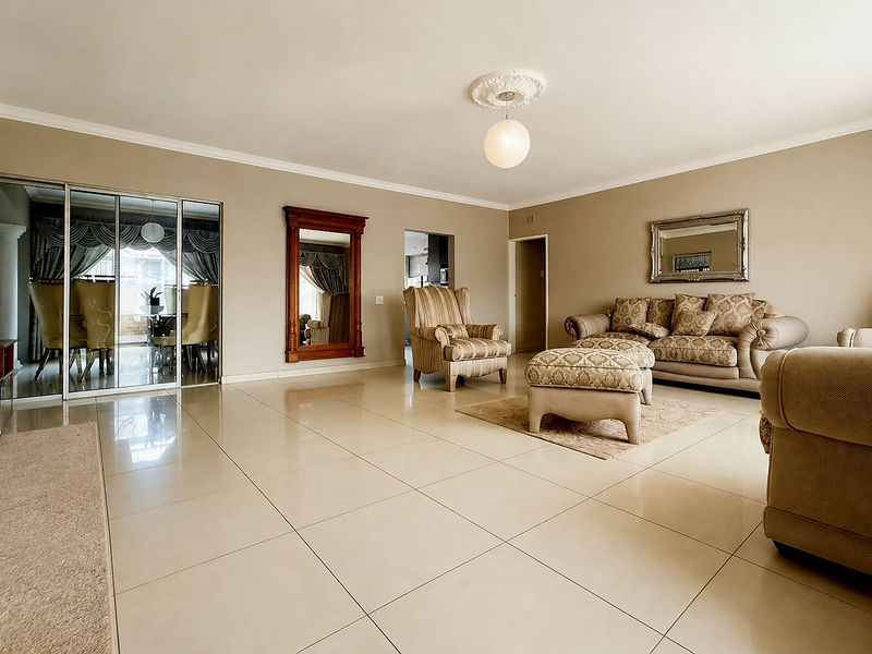 Spacious living room featuring large format porcelain floor tiles, decorative ceiling rose, and sliding glass doors leading to an adjacent dining area.