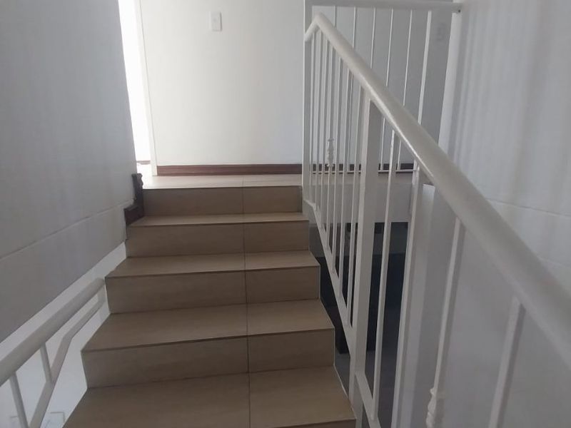 A simple staircase featuring tiled steps and a white metal balustrade, providing access between levels in this townhouse.