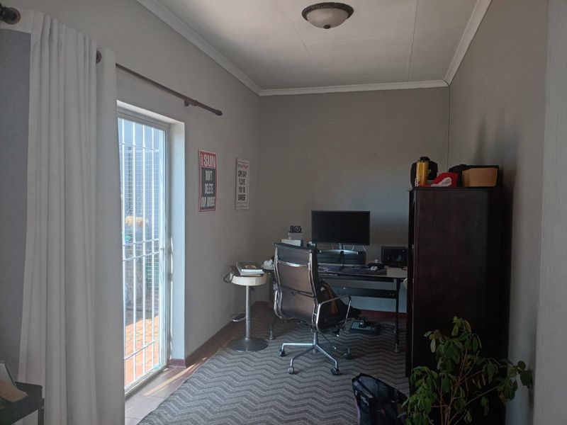 A functional home office space featuring neutral walls, a ceiling light fixture, and a sliding glass door providing access to the exterior.