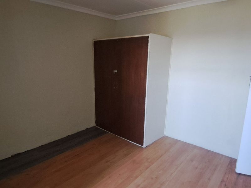 A vacant bedroom featuring laminate flooring, a built-in wardrobe, and neutral wall finishes, offering a blank canvas for personalization.