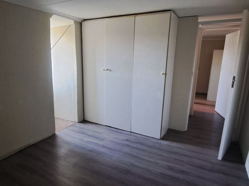 An empty bedroom featuring laminate flooring and a built-in wardrobe, offering a clean and neutral space ready for personalization.
