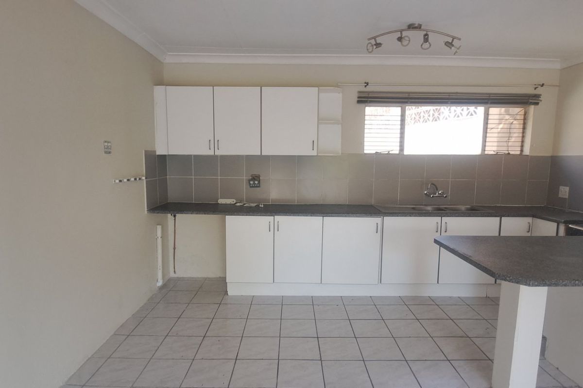 A functional kitchen featuring white cabinetry, laminate countertops, a breakfast bar, and tiled flooring, offering a clean canvas for potential updates.