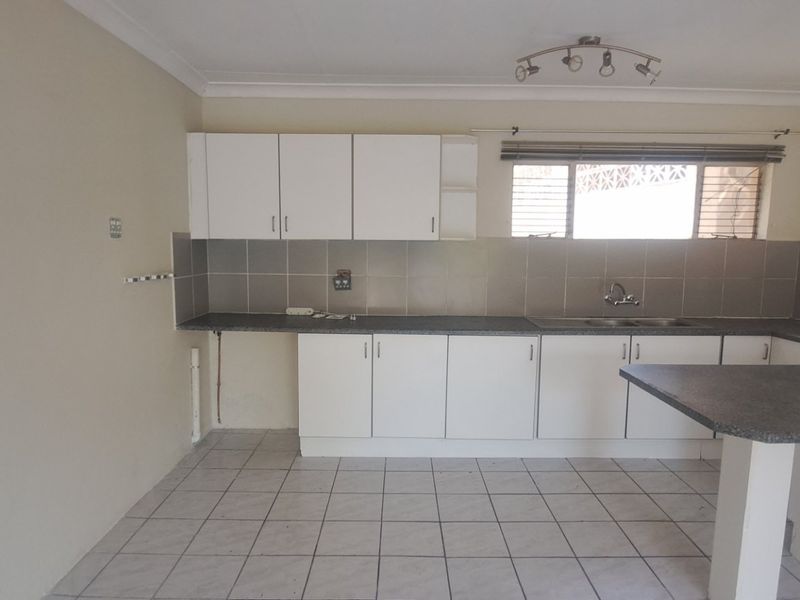 A functional kitchen featuring white cabinetry, laminate countertops, a breakfast bar, and tiled flooring, offering a clean canvas for potential updates.
