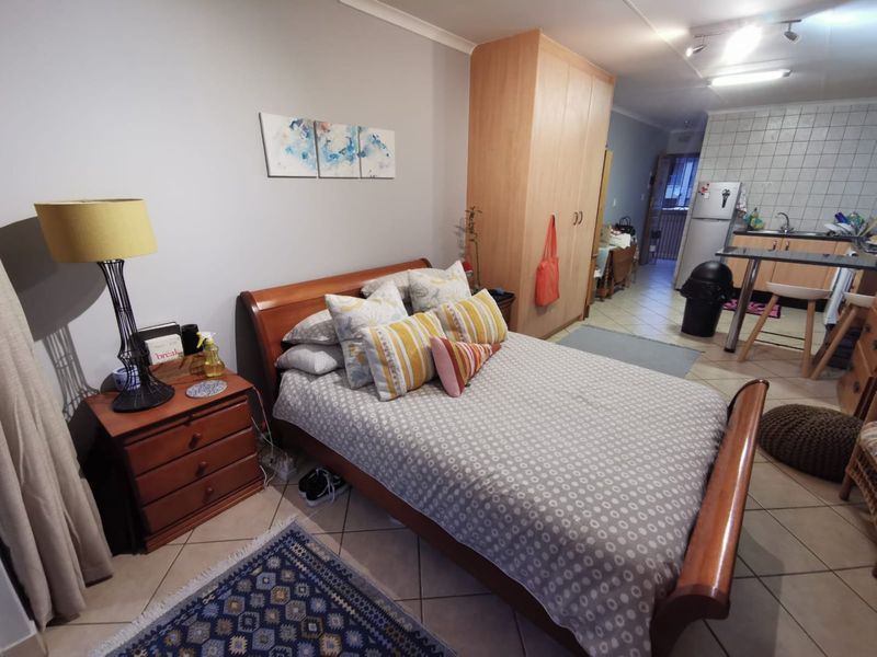 Open-plan studio apartment featuring a combined bedroom and kitchen area with tiled flooring, built-in wardrobe, and functional kitchen cabinetry.
