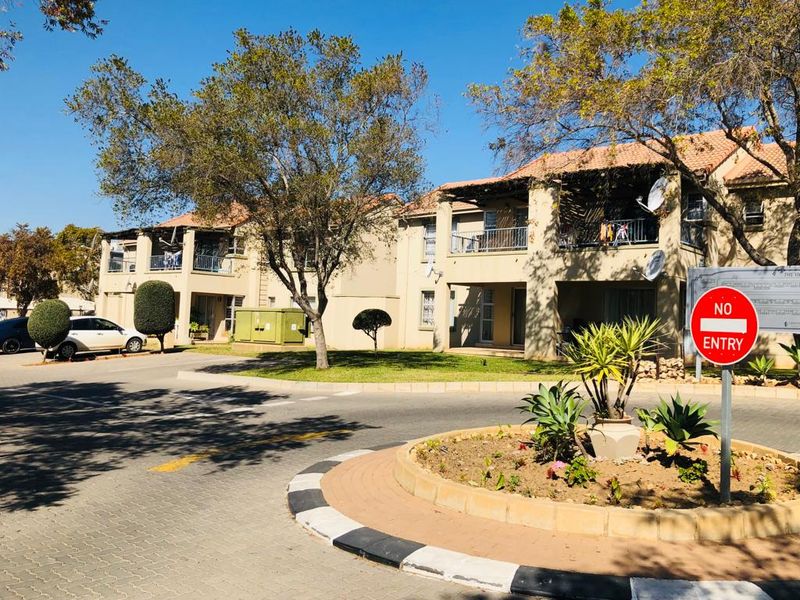 Exterior view of a multi-story apartment complex featuring paved driveways, landscaped garden areas, and private balconies.
