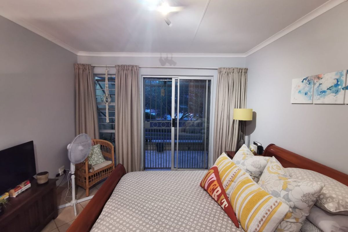 A bedroom featuring tiled flooring, cove cornicing, and a sliding glass door with an integrated security gate leading to an outdoor area.