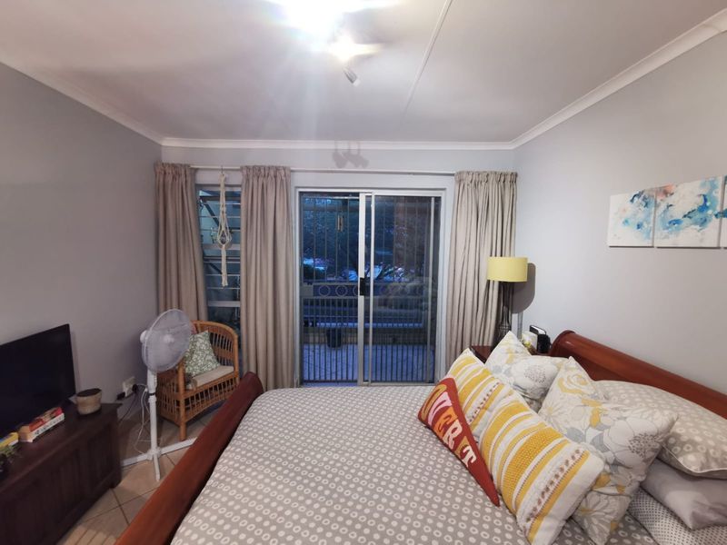 A bedroom featuring tiled flooring, cove cornicing, and a sliding glass door with an integrated security gate leading to an outdoor area.