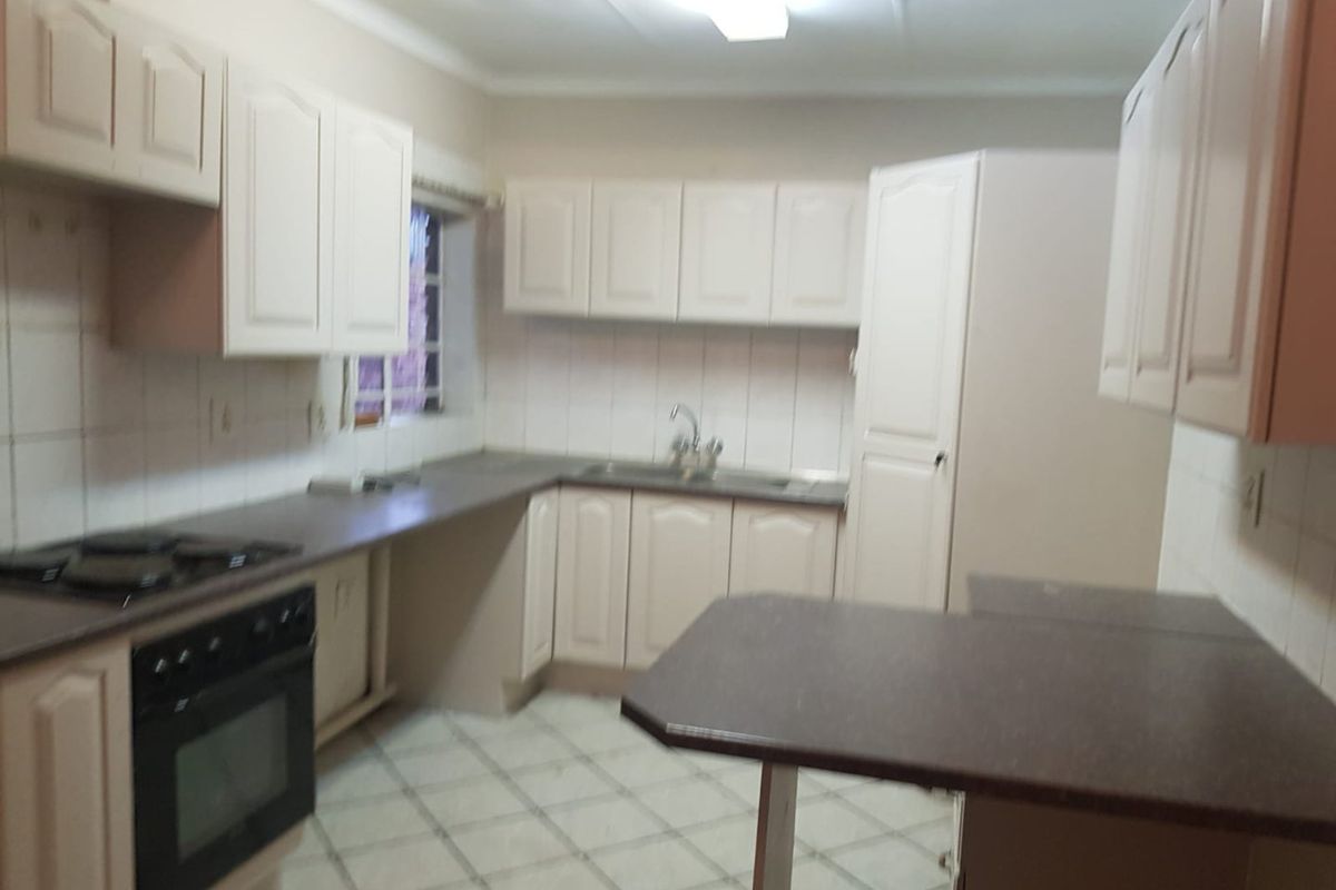 A functional kitchen featuring built-in cabinetry, laminate countertops, a built-in oven with hob, and tiled flooring.