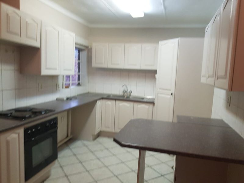 A functional kitchen featuring built-in cabinetry, laminate countertops, a built-in oven with hob, and tiled flooring.