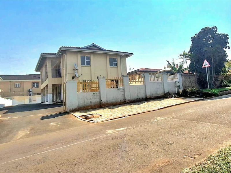 Exterior view of the apartment complex featuring a perimeter wall, gated entrance, and paved driveway area.