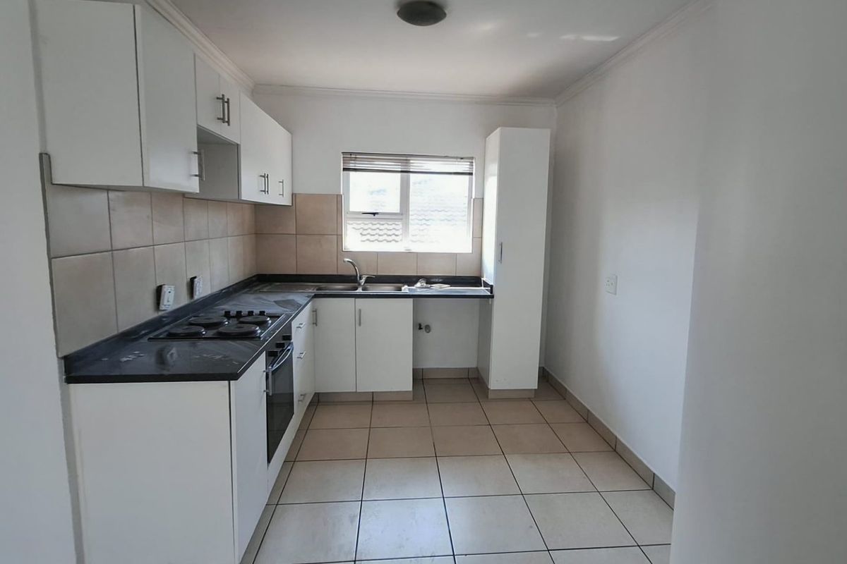 A functional kitchen featuring white cabinetry, dark laminate countertops, a gas hob, built-in oven, and tiled flooring with a neutral splashback.