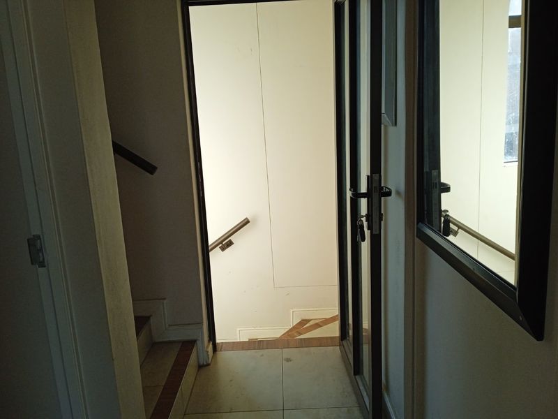 A functional hallway area featuring a staircase with a handrail and a glass door, providing access between levels.