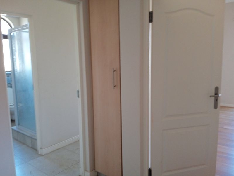 A functional hallway area featuring built-in storage cabinetry, tiled flooring, and direct access to an adjacent bathroom with a shower enclosure.