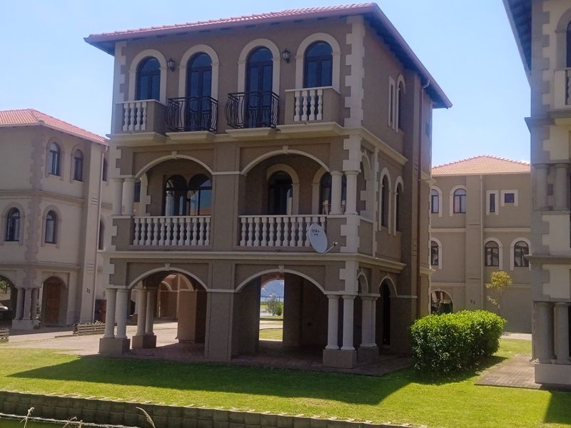 A multi-story residential building featuring classic arched windows, decorative balustrades, and covered patio areas overlooking a landscaped garden.