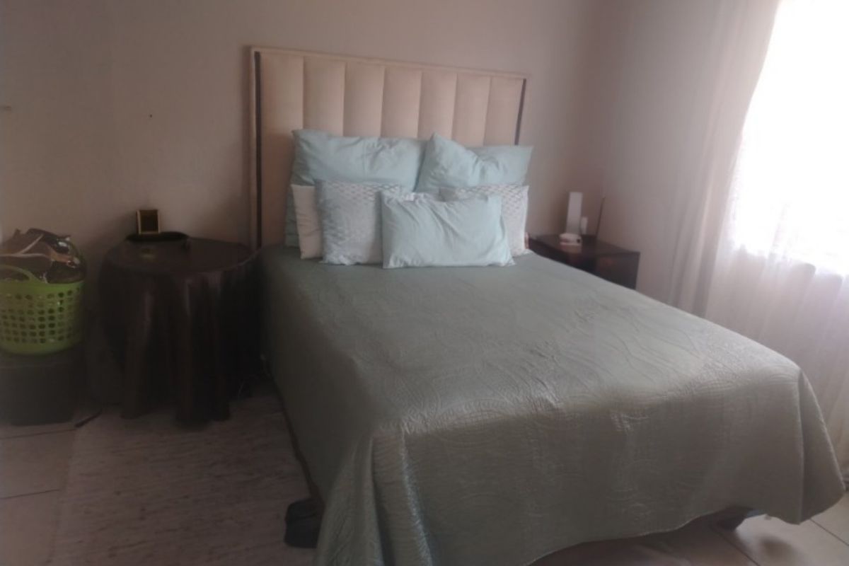 A standard bedroom featuring tiled flooring and natural light from a side window.