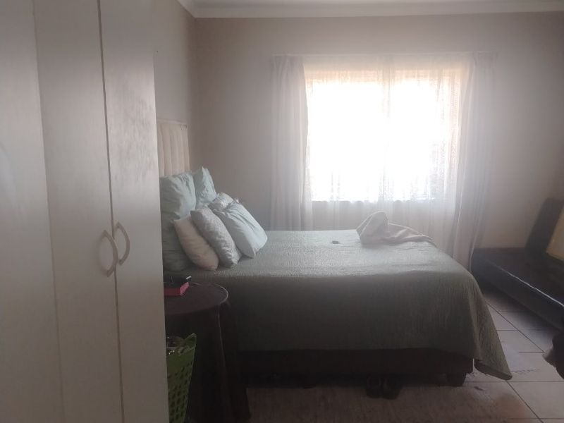 A bedroom featuring tiled flooring, a built-in wardrobe, and a ceiling-mounted light fixture, offering a functional space with natural light.