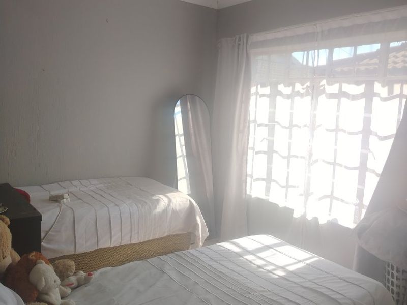 A bedroom featuring neutral wall finishes, a window with security bars, and a ceiling-mounted spotlight fixture.