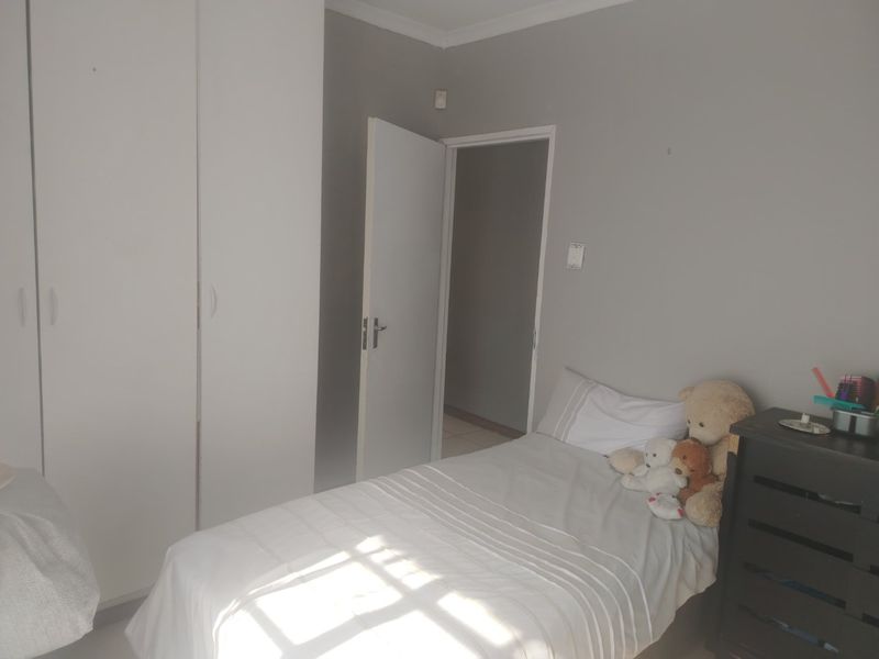 A functional bedroom featuring neutral wall tones and built-in cupboards, providing essential storage space.