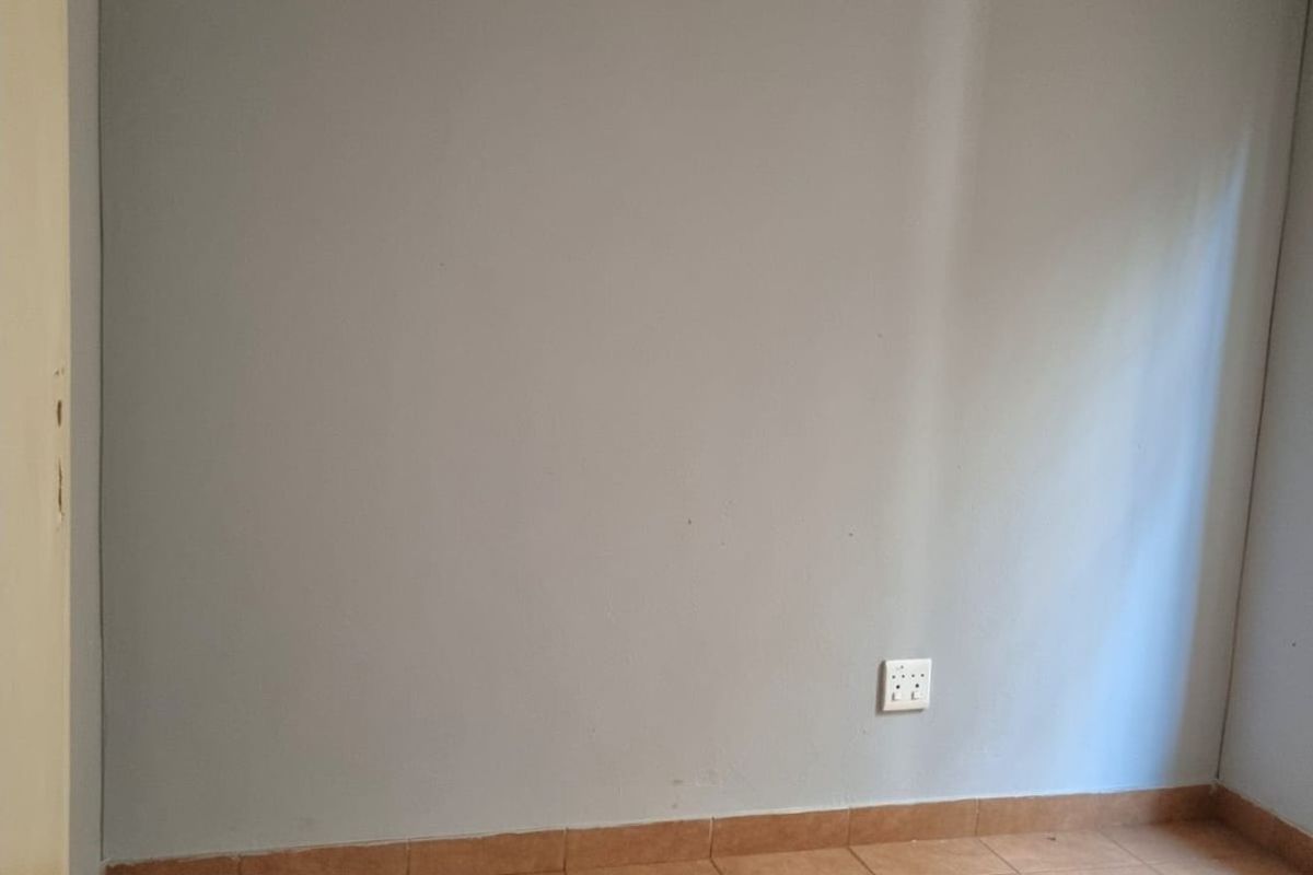 An empty bedroom featuring neutral grey walls, ceramic floor tiles, and a coved ceiling cornice, providing a blank canvas for personalization.