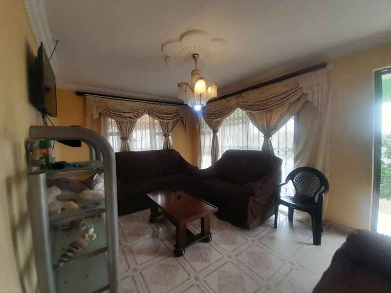 A living room featuring tiled flooring, a decorative ceiling rose with a chandelier, and cornice detailing.