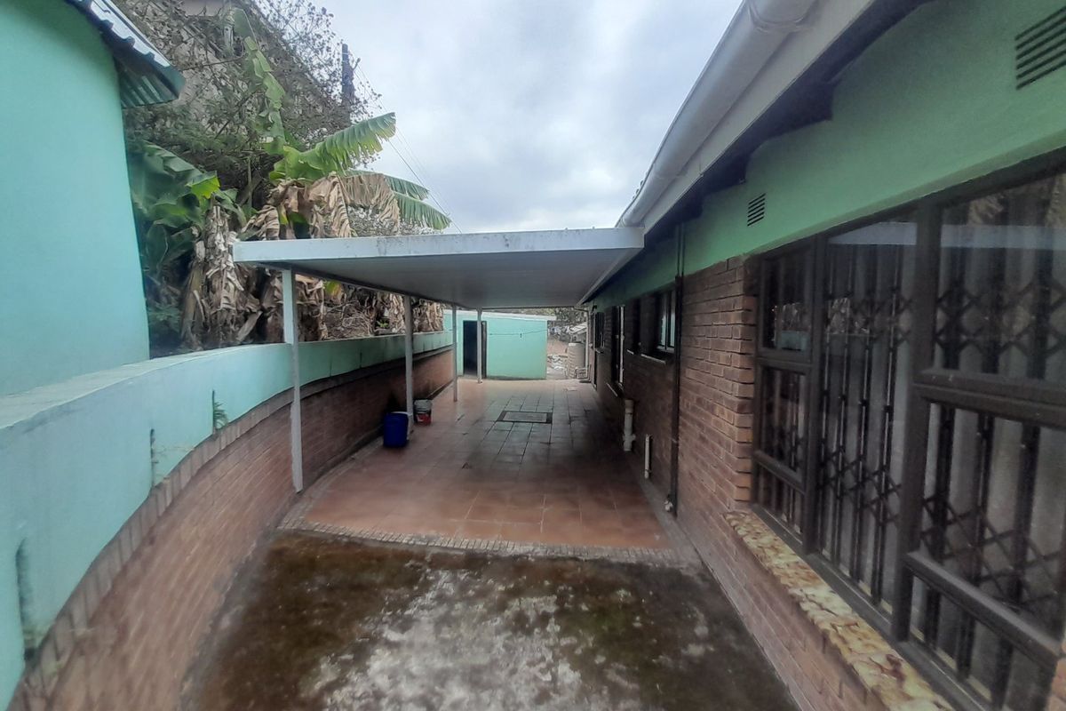 A side exterior area featuring a covered carport, tiled flooring, and brick wall construction, providing functional outdoor space along the side of the house.