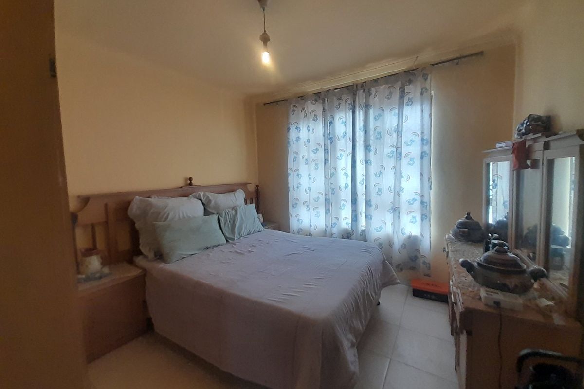 A functional bedroom featuring tiled flooring and a built-in headboard, offering a neutral canvas for potential updates.