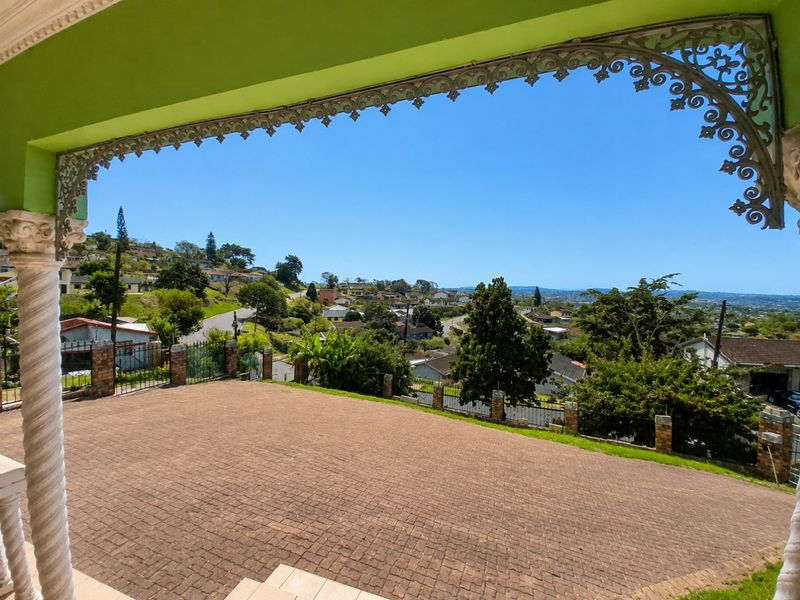 A spacious covered patio featuring decorative wrought iron trim and brick paving, offering elevated views over the surrounding residential neighborhood.