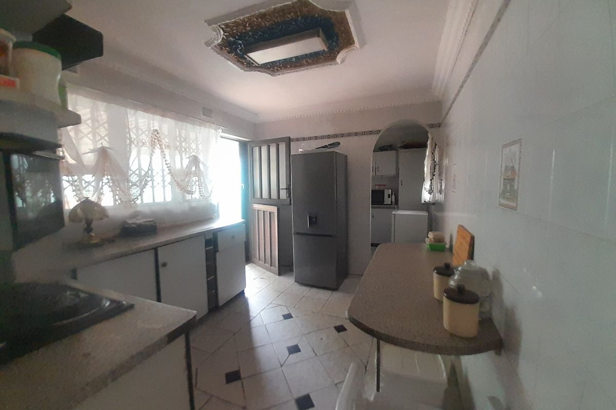 A dated kitchen featuring built-in cabinetry, tiled flooring, and a breakfast counter, offering potential for a modern renovation.