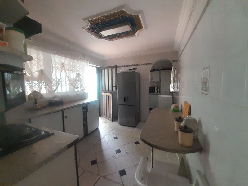 A dated kitchen featuring built-in cabinetry, tiled flooring, and a breakfast counter, offering potential for a modern renovation.