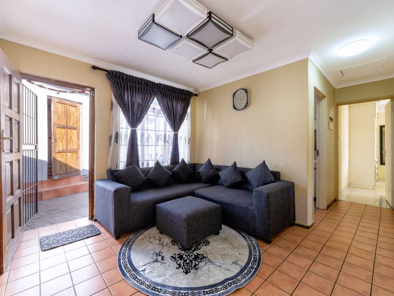 A cozy living room featuring tiled flooring, modern square ceiling light fixtures, and direct access to an exterior entrance area.