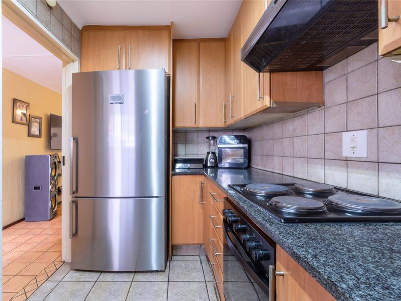 A functional kitchen featuring laminate cabinetry, granite countertops, a ceramic tile backsplash, and built-in cooking appliances with tiled flooring throughout.