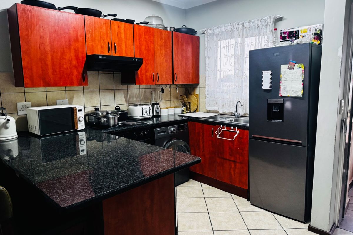 A functional kitchen featuring dark wood cabinetry, granite countertops, tiled backsplash, and integrated fixtures, offering a practical layout for daily meal preparation.