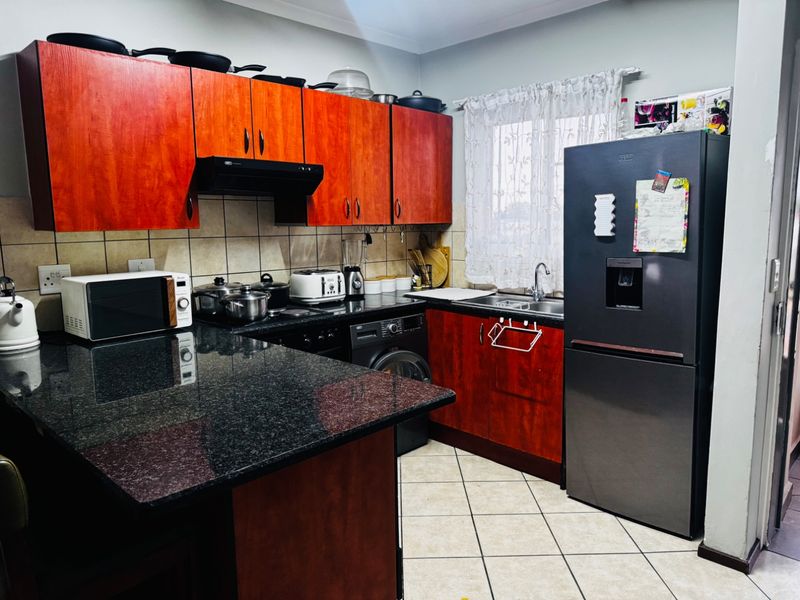 A functional kitchen featuring dark wood cabinetry, granite countertops, tiled backsplash, and integrated fixtures, offering a practical layout for daily meal preparation.
