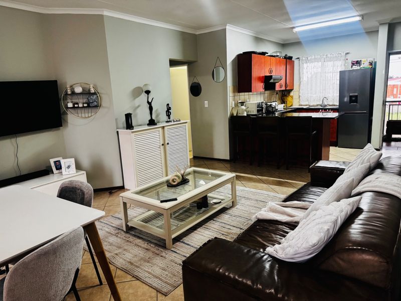 Open-plan living area featuring a kitchen with dark wood cabinetry, a breakfast island, and tiled flooring throughout the combined lounge and dining space.
