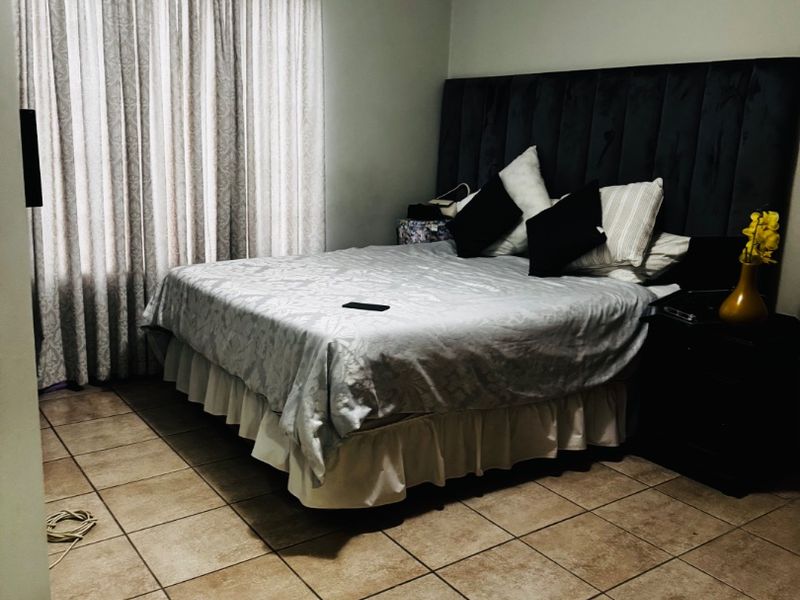 A bedroom featuring tiled flooring and neutral wall finishes, providing a functional space with a classic layout.