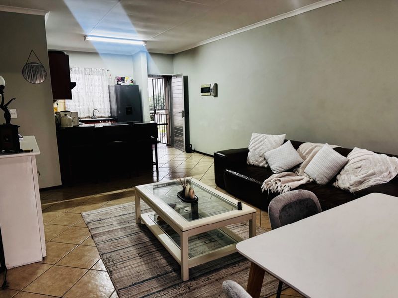Open plan living and kitchen area featuring ceramic tiled flooring, functional cabinetry, and direct access to an exterior entrance.