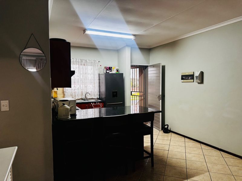 A functional kitchen featuring dark cabinetry, granite countertops, tiled flooring, and direct access to an exterior door.
