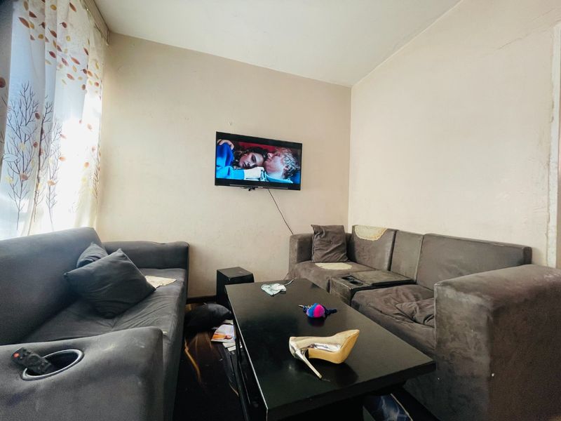 A compact living room area featuring neutral wall finishes, suitable for renovation or restyling to enhance the space's overall appeal.